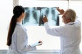Two doctors examine radiograph for medical xray diagnosis in sterile room.