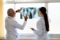 Two doctors examine radiograph for medical xray diagnosis in sterile room.