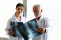 Two doctors examine radiograph for medical xray diagnosis in sterile room.