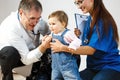 Two doctors examining a small child in a denim overalls