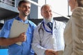 Two doctors and female patient shaking hands before consultation in the office of a modern medical center Royalty Free Stock Photo