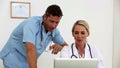 Two doctors using a laptop together in their office