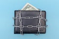 Two dollars are in the wallet. Concept of the wallet is locked with a chain. Blue background. Bankrupt. Money is tight