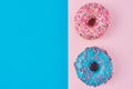 Two donuts glazed with sprinkles on a pink and blue background with copy space, top view flat lay. Minimalism concept Royalty Free Stock Photo