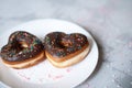 two donuts in a heartshape on a gray background on a white plate. Concept for Valentine's Day. Valentine's Day Royalty Free Stock Photo