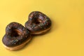 two donuts in a heartshape on a yellow background. Concept for Valentine's Day. Valentine's Day bakery. space Royalty Free Stock Photo