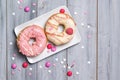 Two donuts on a plate decorated with smarties and sprinkles hearts, wooden background