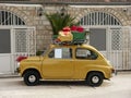 Little yellow vintage car with red, green and yellow gift boxes on its roof side view Royalty Free Stock Photo