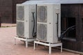 two double condensing units of air conditioner on the ground level near granite building wall