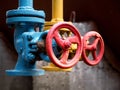 Two drain valves blue and yellow with red steering wheels over b