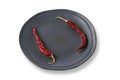 Two dried hot peppers along the edges of a handmade gray ceramic plate isolated on a white background. Template for Royalty Free Stock Photo