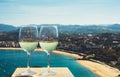 Two drink glass white wine standing on background blue sea top view city coast yacht from observation deck, romantic toast