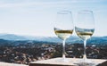 Two drink glass white wine standing on background blue sea top view city coast yacht from observation deck, romantic toast