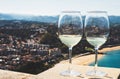 Two drink glass white wine standing on background blue sea top view city coast yacht from observation deck, romantic toast