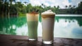 two drinks sitting on a table next to each other on a lake side table with a view of the water and trees in the background Royalty Free Stock Photo