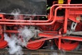 Two old red driving wheels of a steam locomotive engine with steam