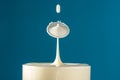 Two drops of milk fall into the long drink glass hitting each other then the liquid surface is shaped like a mushroom