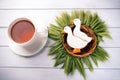 Two duck shaped ginger cookies with basket nest wreath with spikelets top view with tea cup on a white wooden background. Royalty Free Stock Photo