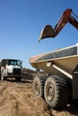 Two dump trucks and an excavator boom at a construction site