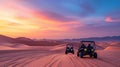 Two dune buggies paused on a desert at sunset, with a backdrop of vast sand dunes under a colorful sky Royalty Free Stock Photo