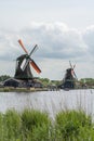 Two dutch mills with orange wings under the cloudy sky