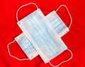 Two ear-loop masks are on a red background, laying in cross Royalty Free Stock Photo