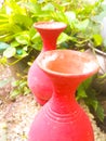 Two earthen pots of red color placed under the sunlight in a garden