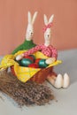 Two Easter bunny near the basket with colorful painted eggs and flowers of lavand.