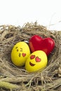 Two Easter eggs painted with emojis, one in love and other kissing, placed into a nest in isolated white background Royalty Free Stock Photo