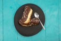 Two eclair cakes on a black ceramic plate, and blue wooden boards table, flat lay Royalty Free Stock Photo