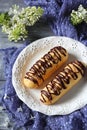 Two eclair on a white plate on a purple cloth Royalty Free Stock Photo