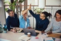 Group of laughing coworkers high fiving during an office meeting