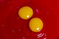 Two egg yolks with white and yellow in a red bowl for cake preparation