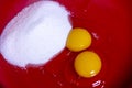 Two egg yolks with white and yellow in a red bowl for cake preparation