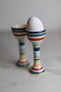 Two eggcups on a marble table with colorful stripes and only one Royalty Free Stock Photo