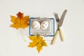 Two eggs with a joyful smile and a sad one lie in a supermarket basket next to autumn leaves and a knife with a fork on Royalty Free Stock Photo