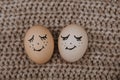 Two eggs with a painted face lie on a scarf Royalty Free Stock Photo