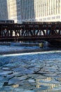 Two el trains travel over a blue and frozen Chicago River with ice chunks. Royalty Free Stock Photo