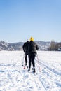 Two elderly athletes in sportswear skiing across field covered with snow