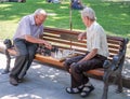 Two elderly grandfather playing on a park bench in chess