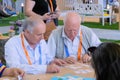 Two elderly men playing intellectual game at smart exhibition