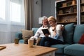 Two elderly people senior couple man and woman looking at a family photo smile and hug while sitting at home on sofa. memories and