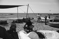 Two elderly retired fishermen looking at a group of young people on a beach in Malaga, Spain