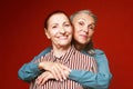 Two elderly women friends hugging on red background. Royalty Free Stock Photo