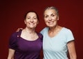 Two elderly women friends hugging on red background. Lifestyle and old people concept. Royalty Free Stock Photo