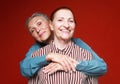 Two elderly women friends hugging on red background. Lifestyle and old people concept. Royalty Free Stock Photo