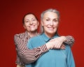Two elderly women friends hugging on red background. Lifestyle and old people concept. Royalty Free Stock Photo