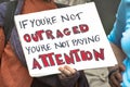 Two elderly women hold an outrage sign in protest