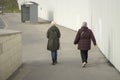 Two elderly women walk down the street to a bus stop. Warm casual clothes. Grey autumn day. Traffic Royalty Free Stock Photo