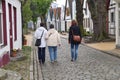 Two elderly women walking along a neat cobbled path together with a younger woman by their side